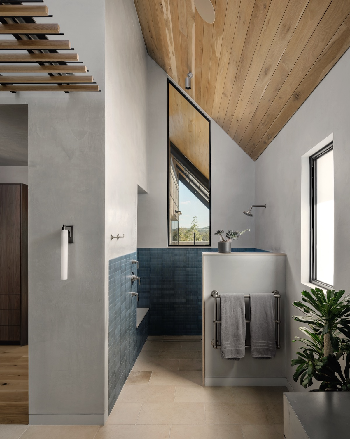 Smooth gray plaster walls accent angular modern windows in the bathroom of a Blanco, Texas ranch compound.