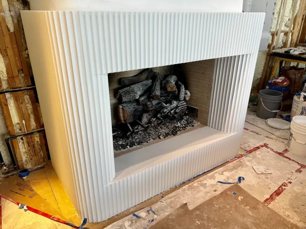 Video of plaster craftsmen running moldings on the bench for a fluted plaster fireplace